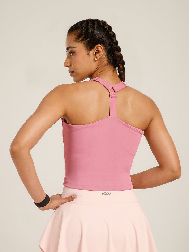 Woman wearing a pink top with thin straps on a plain background
